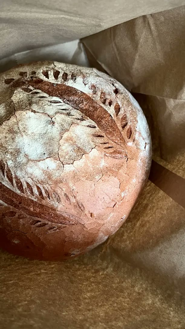 A scored round sourdough loaf on brown paper